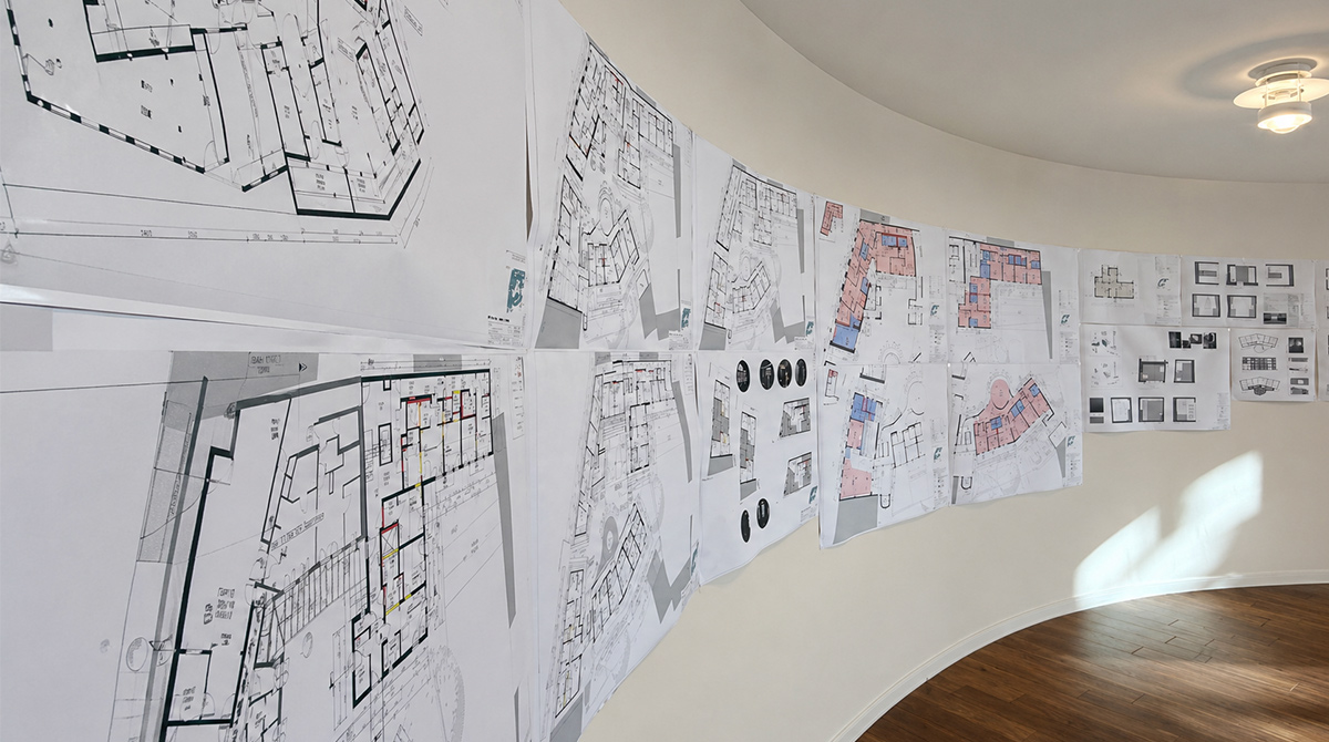 Architekturpläne und Grundrisse des Umnutzungsprojekts Neue Sülze in Lüneburg, an einer geschwungenen Wand aufgehängt